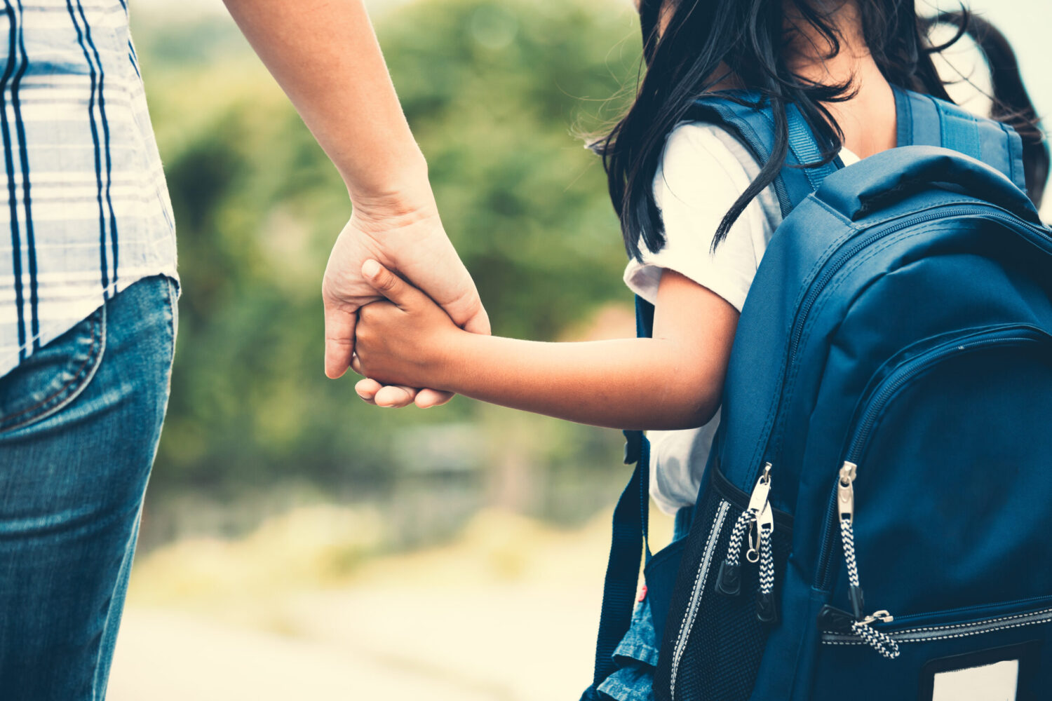 Back to school. Cute asian pupil girl with backpack holding her mother hand and going to school in vintage color tone