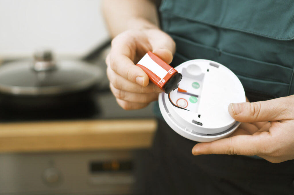 Man checking battery in smoke detector in the kitchen.