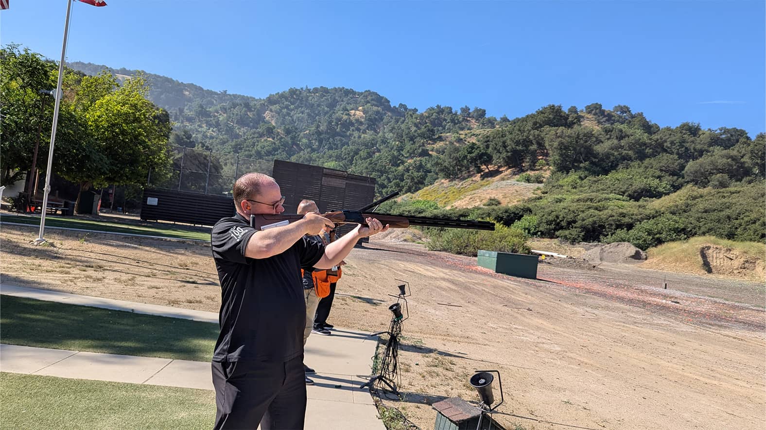 John Scott aiming a shotgun at a clay target during the Clays for K9s trapshooting competition.