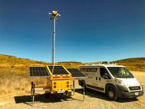 Valley Alarm mobile security trailer with solar panels deployed at remote Castaic industrial site with service van
