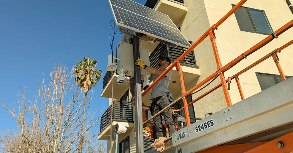 Valley Alarm technicians installing a solar pole-mounted security camera at a construction site in North Hollywood