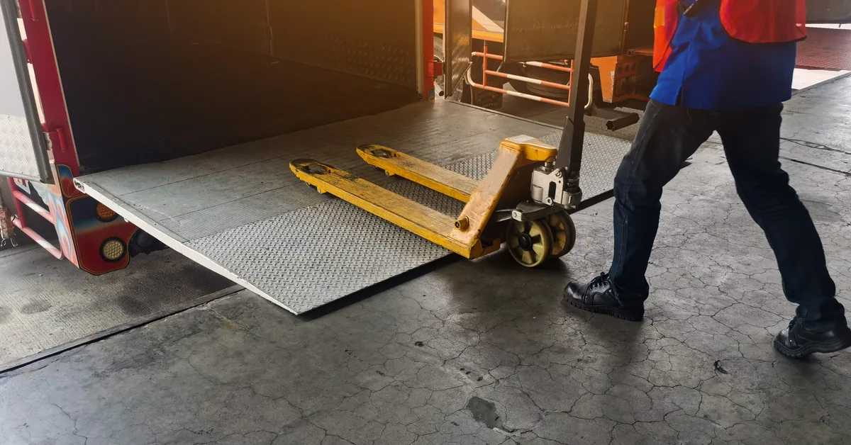 Worker moving a pallet jack at a warehouse loading dock where access control governs entry